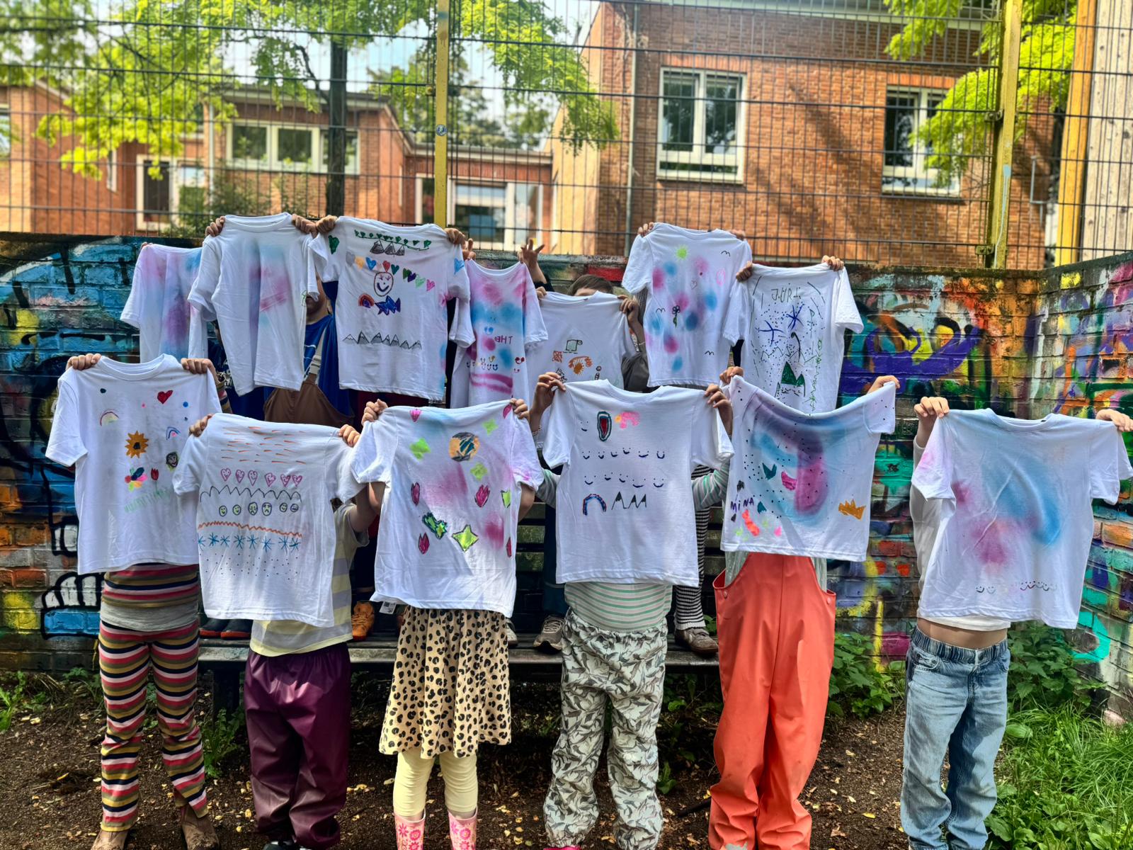 Kinder zeigen ihre selbst gestalteten T-Shirts